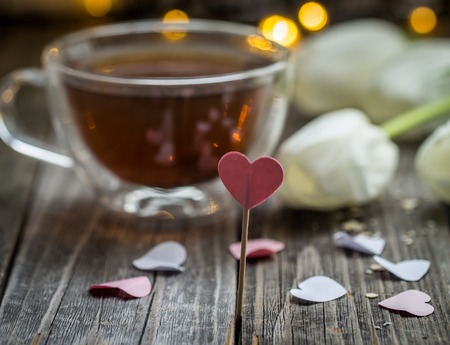 Valentine's day beautiful white tulips and tea Cup with heart on wooden background, holiday conceptの写真素材