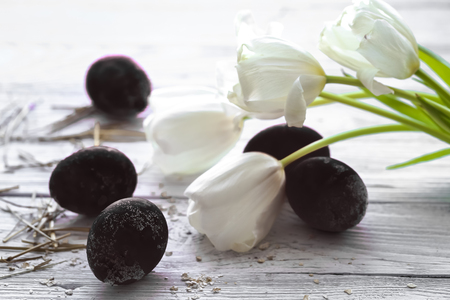 White tulips and black Easter eggs on wooden background ,holiday conceptの写真素材