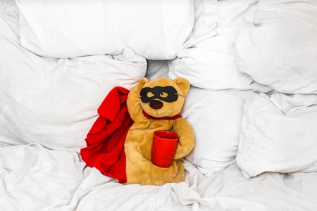 soft toy bear super hero sitting on a white bed ,the concept of leadership,winning, aspirationsの写真素材
