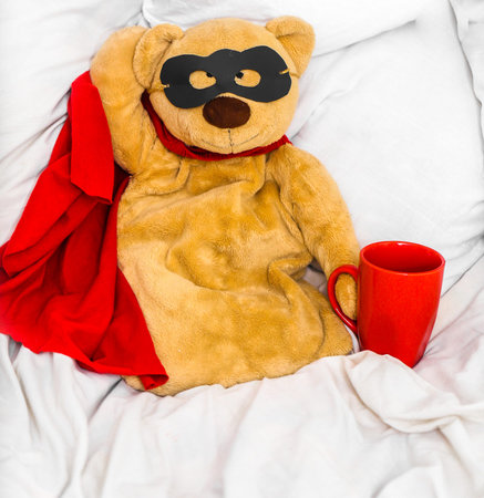 soft toy bear super hero sitting on a white bed ,the concept of leadership,winning, aspirations