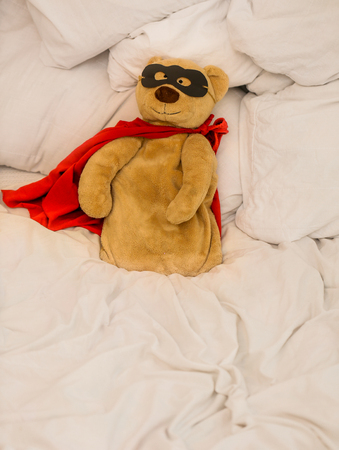 soft toy bear super hero sitting on a white bed ,the concept of leadership,winning, aspirationsの写真素材