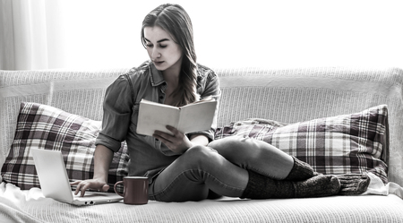 Honey girl cozy with a book and a Cup of black and white photos on the cozy beds,the concept of comfort and relaxationの写真素材