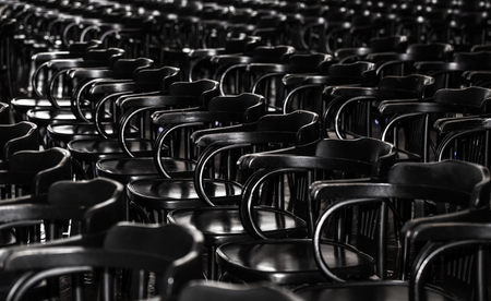 lot of black wooden chairs stand in a diagonal in a large roomの写真素材