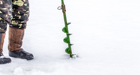 A fisherman on the ice with equipment for winter fishingの写真素材