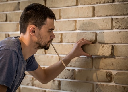 a man working with a beautiful beige brick wall with centimeter ,background ,closeup , place for textの写真素材