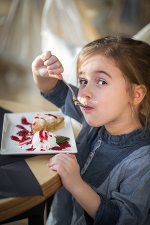 little cute girl in cafe eats a dessert,closeup,concept of holidays and weekendsの写真素材