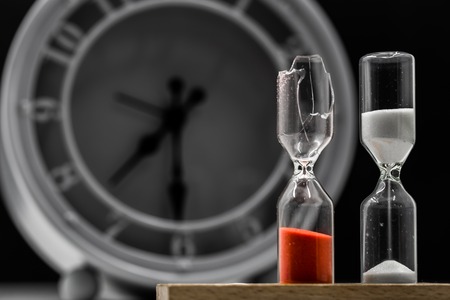 table retro clock with hourglass closeup on black background, time conceptの写真素材
