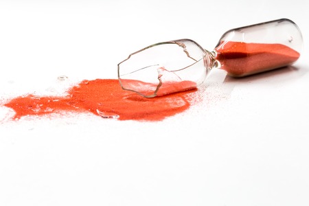 broken glass hourglass with red sand on a white background , time conceptの写真素材