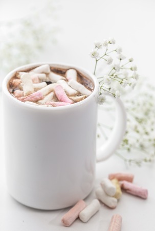 white coffee Cup with colorful marshmallows and small flowers on a white backgroundの写真素材