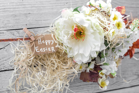 Easter composition with flowers on a light wooden background with a congratulatory card ,concept...