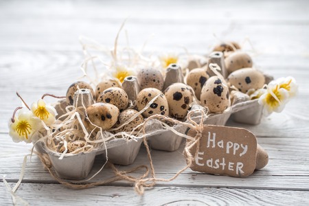 Easter eggs with flowers on a light wooden background with a congratulatory card ,concept holidaysの写真素材