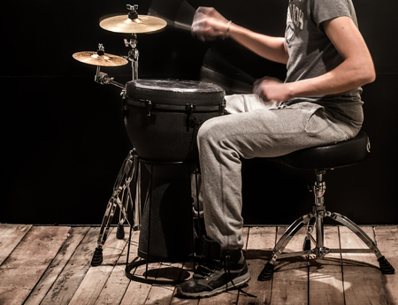 man playing a djembe drum and cymbals on a black background, percussion instruments with a musician and a creative musical conceptの写真素材