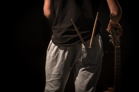 young man with acoustic guitar on black background, creative musical conceptの写真素材