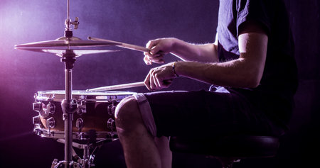 man plays musical percussion instrument with sticks closeup on a black background, a musical concept...