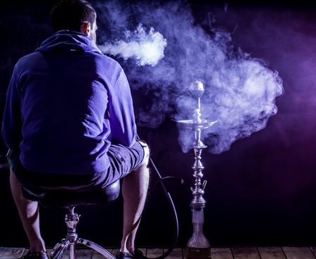 a man smokes a hookah on a black background, holiday concept, beautiful lighting