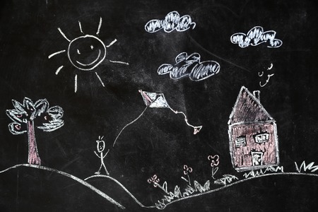 children's chalk drawing of house and sun on black background the concept of nature and the environmentの写真素材