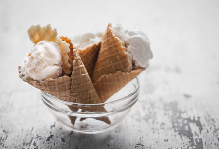 Vanilla ice cream in a waffle cone in a transparent glass bowl on wooden background,concept,...