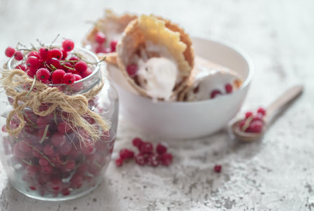ice Vanilla-coconut ice cream in a waffle cone and berries in a clear glass jar on wooden background...