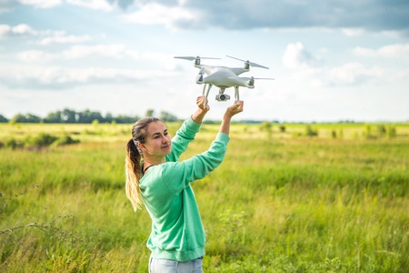 beautiful girl in a field launches the drone into the sky, beautiful backgroundの写真素材