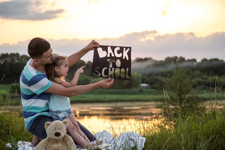 Happy father with cute daughter hard working in nature with the poster in hand back to school, education concept, family valuesの写真素材