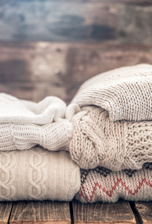 knitted warm cozy sweaters,on wooden background, concept of heat and warm clothing ,place for textの写真素材