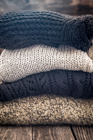 knitted warm cozy sweaters,on wooden background, concept of heat and warm clothing ,place for textの写真素材