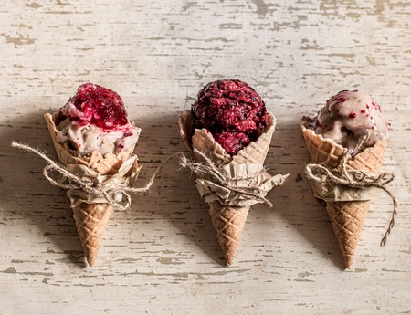 homemade ice cream in a waffle cone with berries on wooden backgroundの写真素材