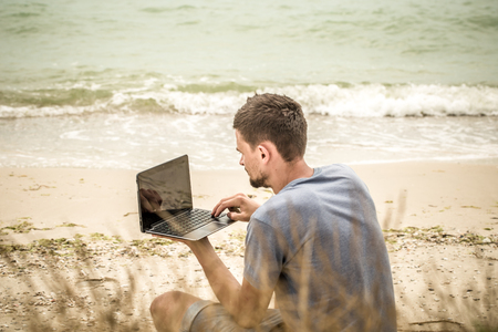 man running on the computer, in nature, to work on the beachの写真素材