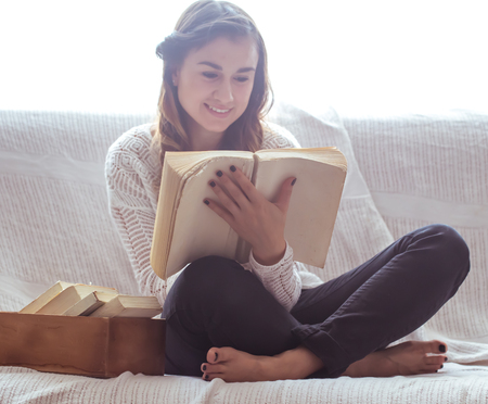 beautiful girl reading a book on the couch ,the concept of leisure and readingの写真素材