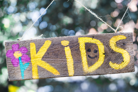 the kids inscription on a wooden sign hanging on a rope, the concept of children and children's holidayの写真素材