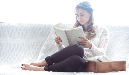 beautiful girl reading a book on the couch ,the concept of leisure and readingの写真素材
