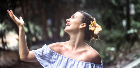 Beautiful young girl in dress is happy the rain tropical forest along the road