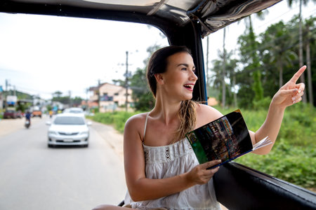 young beautiful girl tourist in a Thai taxi, considering the book -map , concept of travel