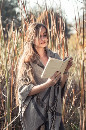 beautiful girl reading a book in autumn forest , autumn season concept and readingの写真素材