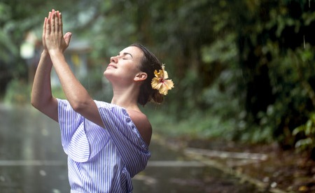 Beautiful young girl in dress is happy the rain tropical forest along the roadの写真素材
