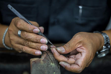 Thai jeweler, handles the jewelry and precious stones in the workshop, the process of jewelry making ,close-upの写真素材
