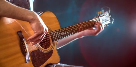 the hand of man playing acoustic guitar, close-up, flash of light, a beautiful light in the...