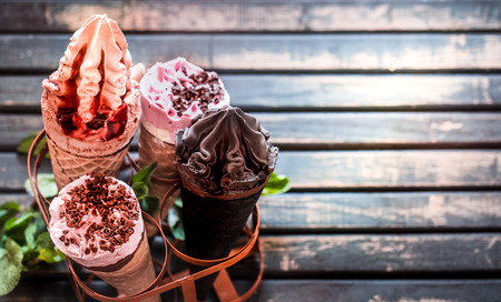 Miscellaneous ice cream cone in a stand on a stylish wooden background, the concept of ice cream and summerの写真素材