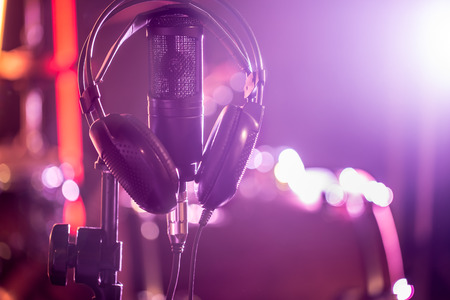 Studio microphone and headphones on a close-up stand, in a recording Studio or concert hall. Beautiful blurred background of colored lights. A musical concept.