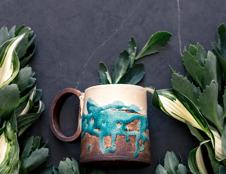 Cup on the background of green leaves, creative backgroundの写真素材
