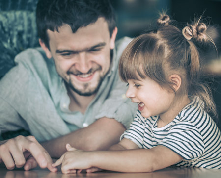 Dad plays with his little daughter at a table in a cafe, celebrating his father's day, family values