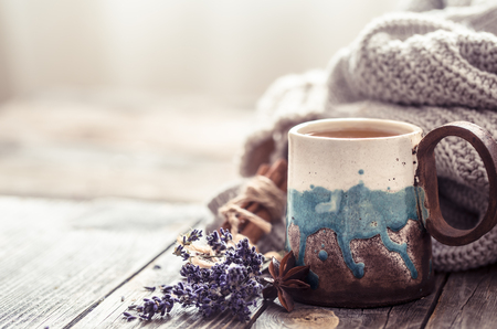 a cup of tea with a knitted sweater on a wooden background, space for textの写真素材