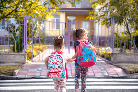 Children go to school, happy students with school backpacks and holding hands together, cross the road, the concept of education with girls, space for textの写真素材