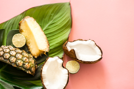 tropical beautiful leaves with fruit on pink background, pineapple, coconut, limeの写真素材