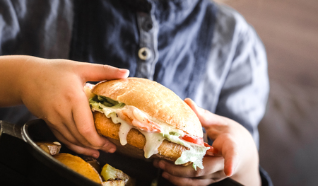 Little girl in a cafe with a sandwich in her hands, concept of a children's fast food mealの写真素材