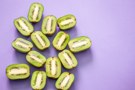 Fresh halves of kiwi on a purple background, pop art. Top view, close-up, creative conceptの写真素材