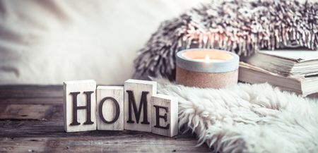 Cozy still life on a wooden background with details in the interior, and wooden letters with the inscription Home and a big beautiful candle, the concept of comfort and home styleの写真素材