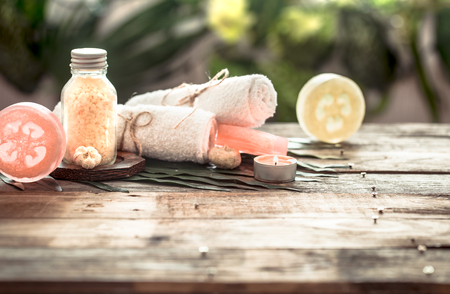 Spa handmade soap with white towels and sea salt, the composition of the tropical leaves with a candle, wooden background with space for text, concept of Spa and relaxation for the bodyの写真素材