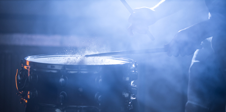 man playing the snare drum on a beautiful colored background, the concept of musical instrumentsの写真素材