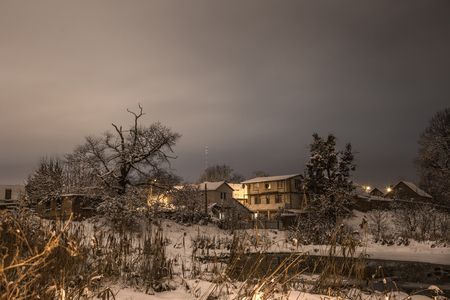 Snow beautiful winter night on the countryside. Street view with snow on trees, houses, roads and lights.の写真素材